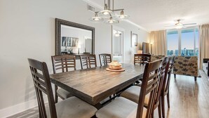 A dining area with a wooden table, chairs, and a chandelier. - 6th Floor Welcoming Condo At Waterscape 490 Feet Of Private Beach (Fort Walton Beach)