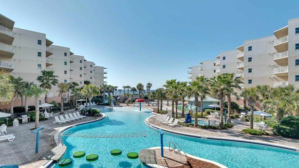 A swimming pool with lounge chairs and palm trees, surrounded by multi-story buildings. - 6th Floor Welcoming Condo At Waterscape 490 Feet Of Private Beach (Fort Walton Beach)