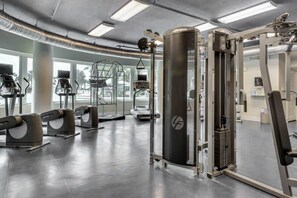Une salle de sport équipée de divers appareils d’exercice, notamment des tapis de course et des appareils de musculation.