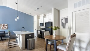 Eine moderne Küche mit weißen Schränken, einem schwarzen Kühlschrank und einer Spüle aus Edelstahl.