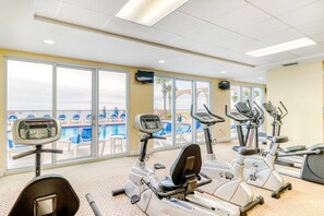 Ein Fitnessraum mit Cardiogeräten und Blick auf ein Schwimmbad.