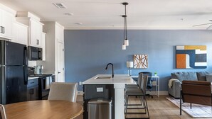 Una cocina moderna con una isla central, un comedor con mesa de madera y una sala de estar con sofá y sillas.