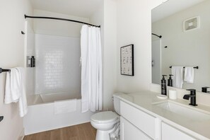 Une salle de bain moderne équipée d’une douche, de toilettes et d’un lavabo, avec des éléments d’aménagement blancs et une zone de douche carrelée.