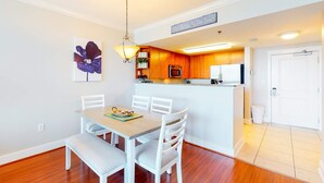 A modern kitchen with wooden cabinets, a white countertop, and a hanging light fixture. - Warm, Welcoming Condo On Okaloosa Island 490 Feet Of Private Beach (Fort Walton Beach)