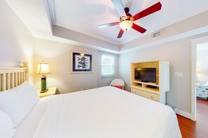 A hotel room with a bed, a ceiling fan, a TV, and a framed picture on the wall. - Warm, Welcoming Condo On Okaloosa Island 490 Feet Of Private Beach (Fort Walton Beach)