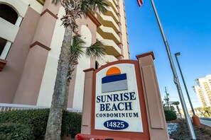 Señal para el condominio Sunrise Beach, con un edificio al fondo.