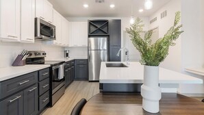 A modern kitchen with dark cabinetry, stainless steel appliances, and a white countertop. - Landing | Incredible 1BD, Clubhouse, Gym (Apopka)