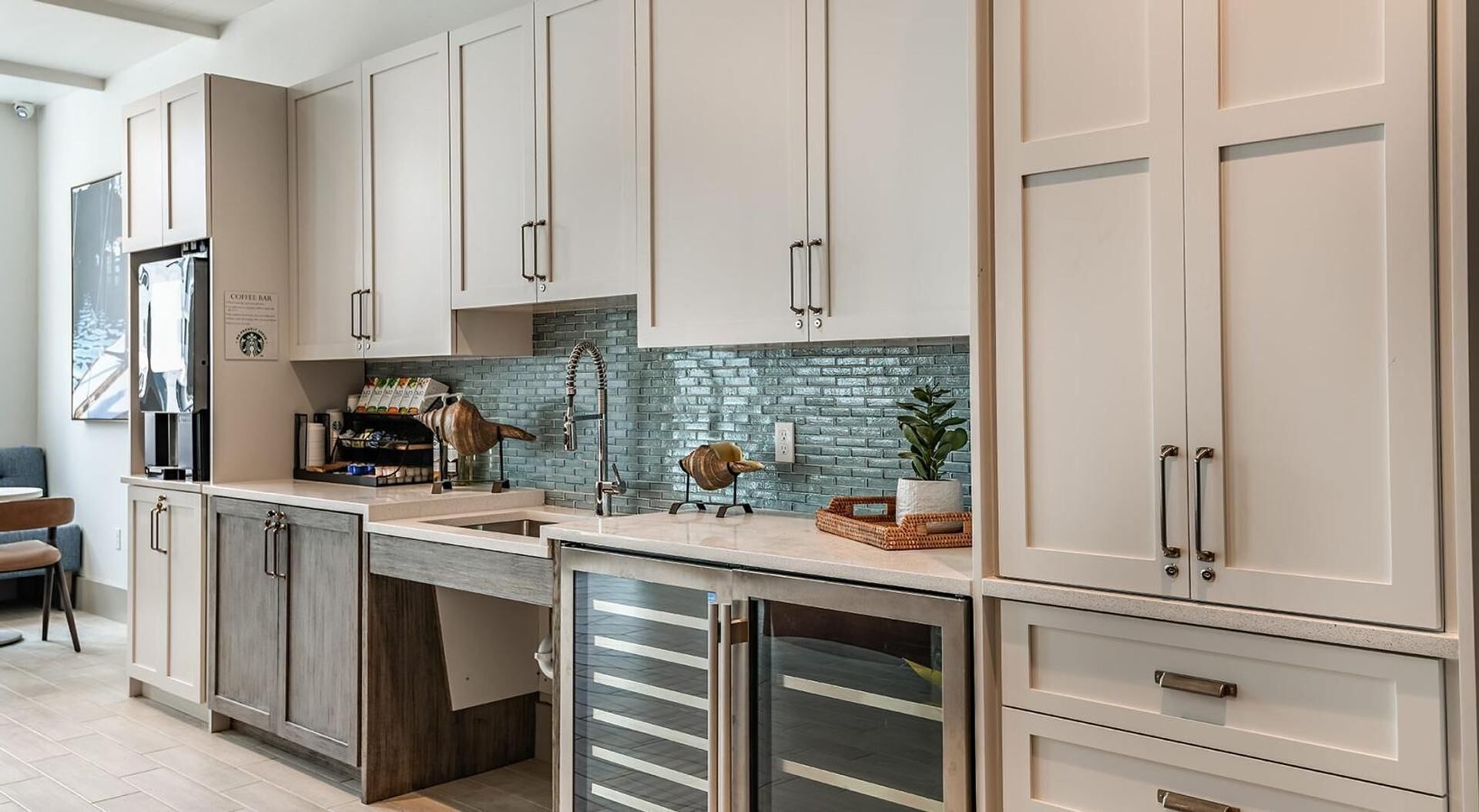 A modern kitchen with light-colored cabinets, a built-in coffee bar, and a brick backsplash.