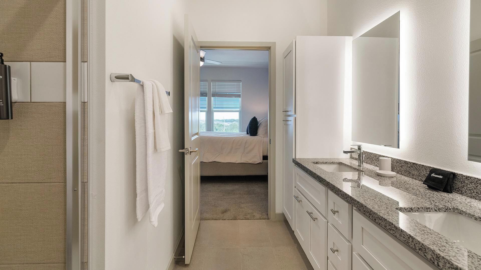 A modern bathroom with a granite countertop, a large mirror, and a walk-in shower.