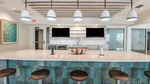 A modern kitchen with a central island, bar stools, pendant lighting, and a large window. - Landing | Stunning 2BD, Gym, Clubhouse (Apopka)