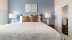 A neatly made bed with white linens, two brown pillows, and two bedside lamps on wooden nightstands. - Landing | Chic 2BD, Gym, Clubhouse (Apopka)