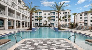 A pool surrounded by a multi-story building with balconies, palm trees, and lounge chairs. - Landing | Chic 2BD, Gym, Clubhouse (Apopka)