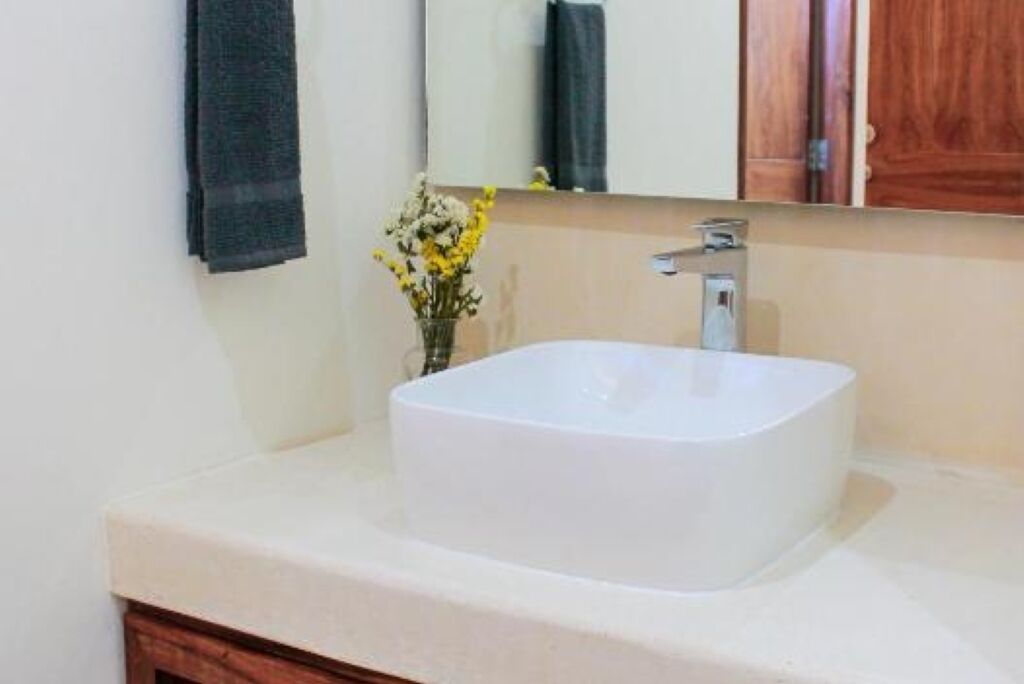 A bathroom with a white sink, a mirror, and a wooden cabinet.