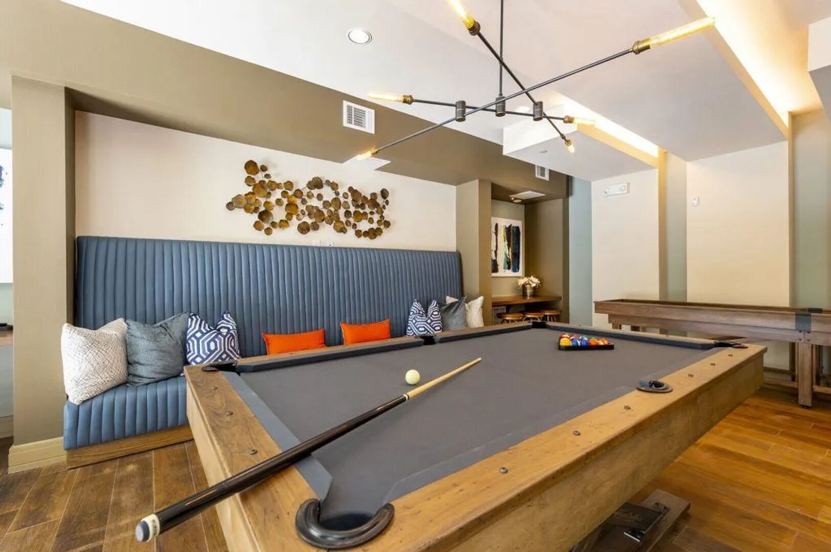 Une table de billard dotée d’une zone de sièges rembourrée en bleu, d’une queue de billard et d’un élément décoratif mural.
