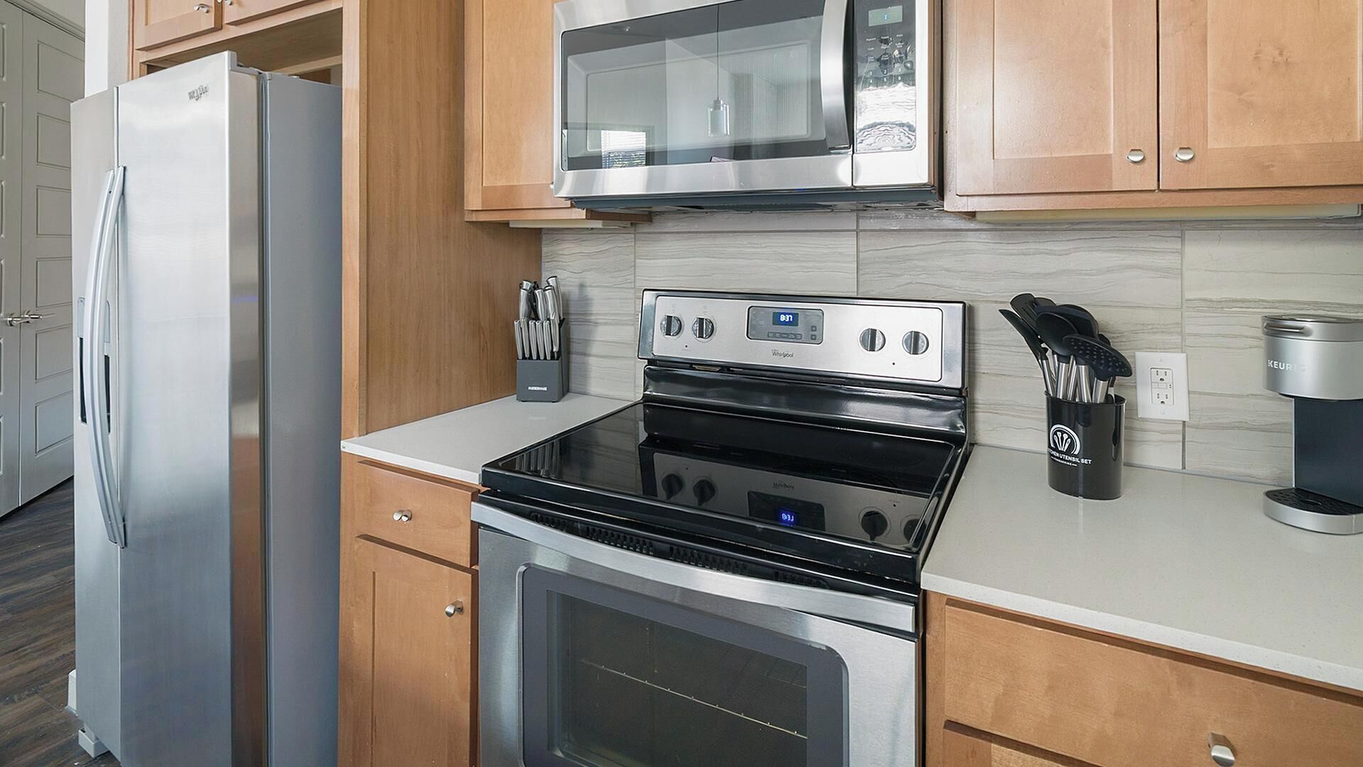 Eine Küche mit einem Edelstahl-Kühlschrank, einer Mikrowelle, einem Backofen und einer Kaffeemaschine.