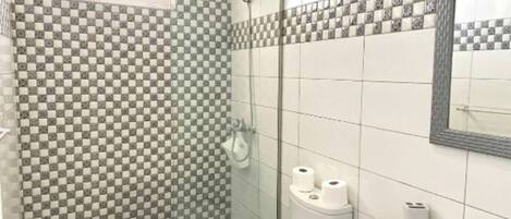 A bathroom with a checkered tile wall, a toilet, a sink, and a shower.