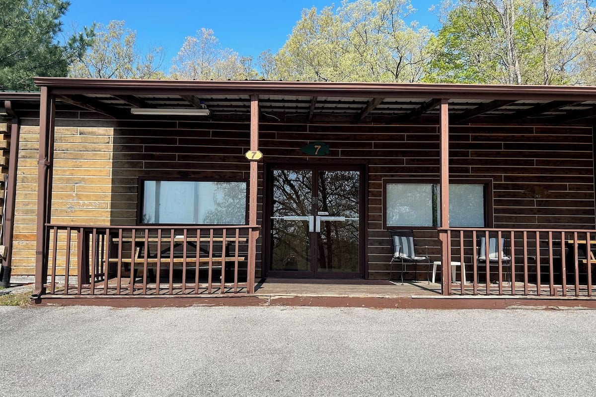 A rustic cabin with a wooden exterior, a covered porch, and a number 7 sign.
