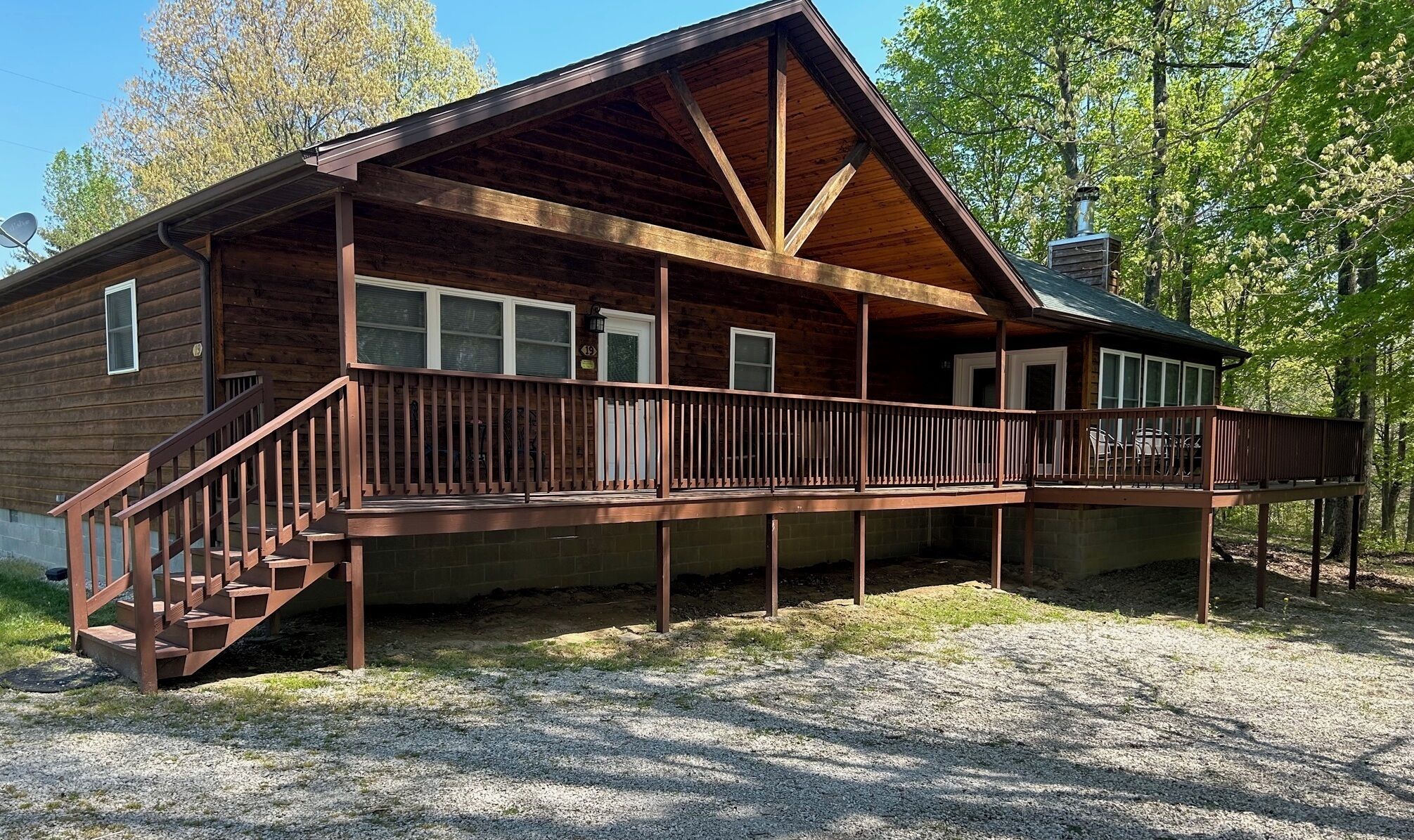 A wooden cabin with a covered porch, a staircase, and a chimney.