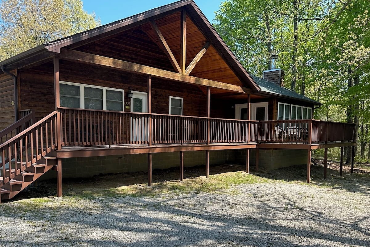 A wooden cabin with a covered porch, a staircase, and a chimney.
