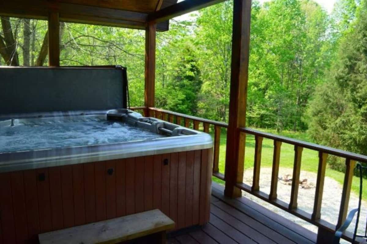 A hot tub on a wooden deck with a view of a forested area.