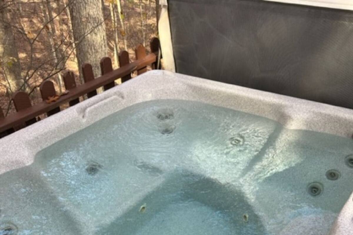 A hot tub with a rectangular shape, a drain in the center, and a wooden fence in the background.