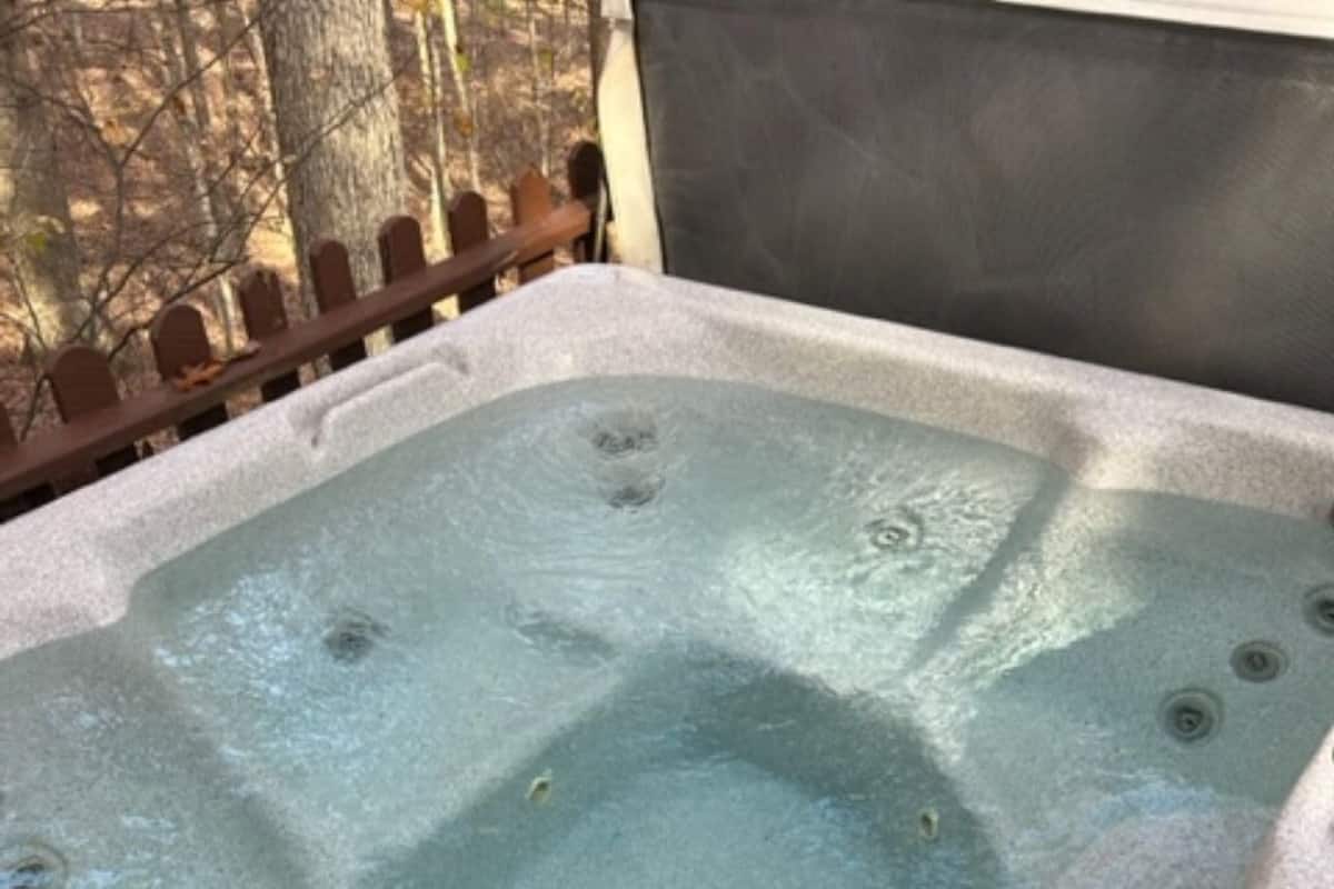A hot tub with a rectangular shape, a drain in the center, and a wooden fence in the background.