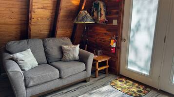 Une pièce chaleureuse avec un canapé gris, une petite table en bois, une lampe et un extincteur.