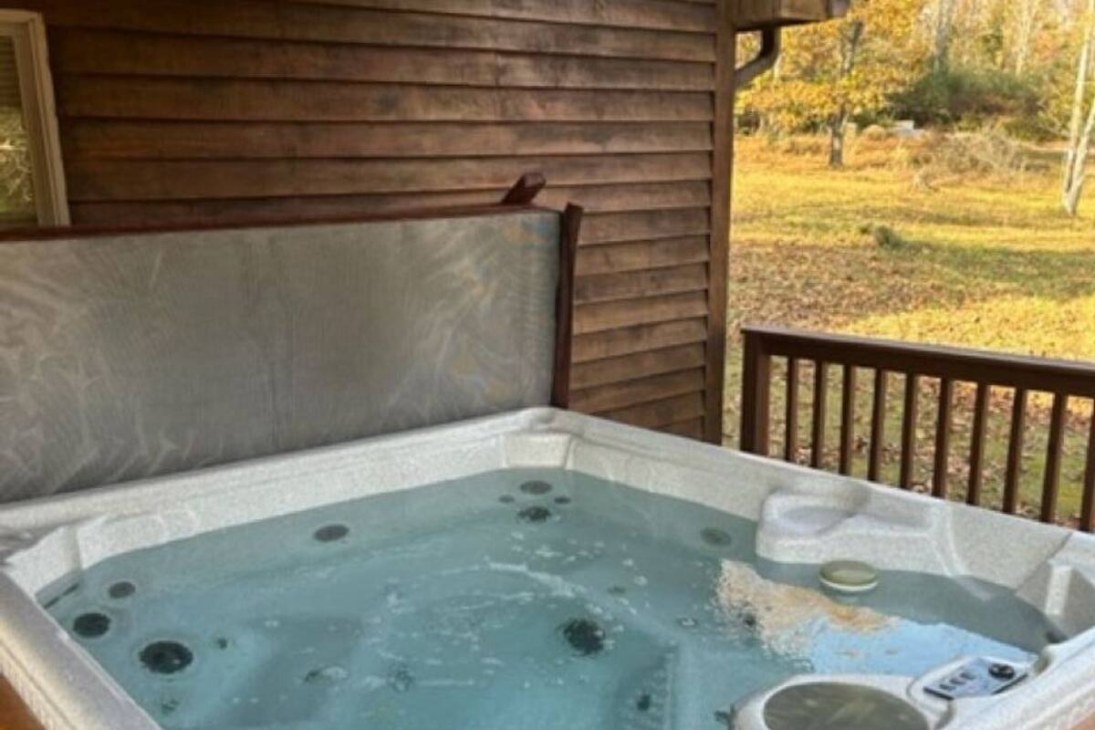 A hot tub in a wooden cabin with a view of a grassy field.