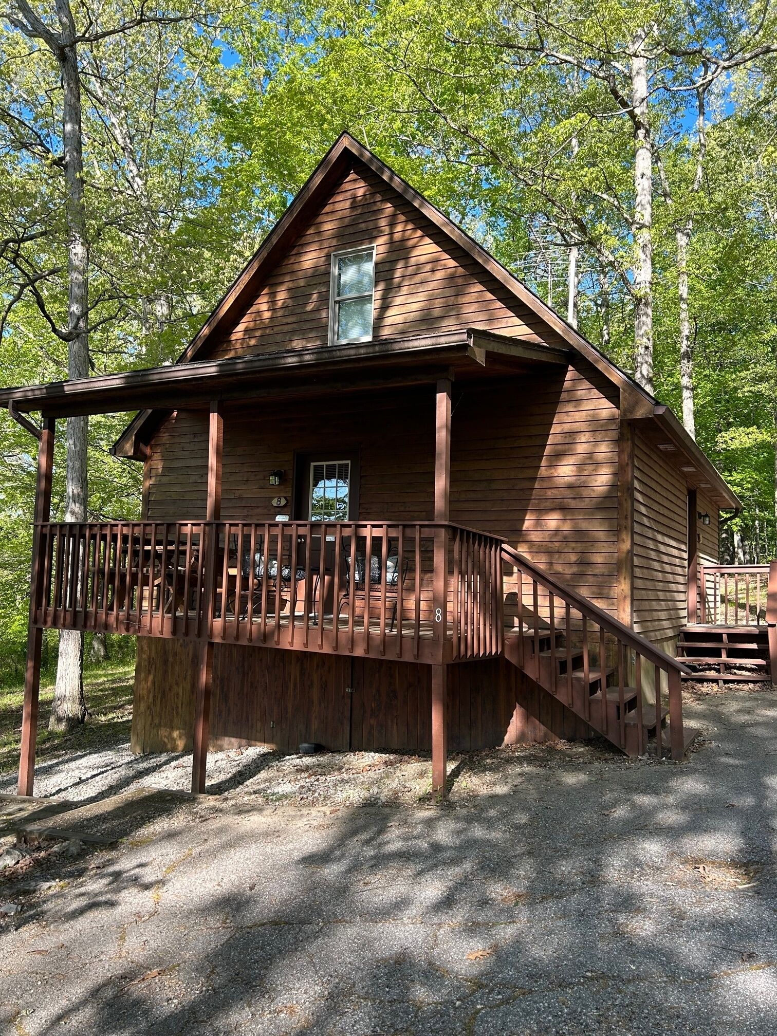 A wooden cabin with a porch, a staircase, and a small deck.