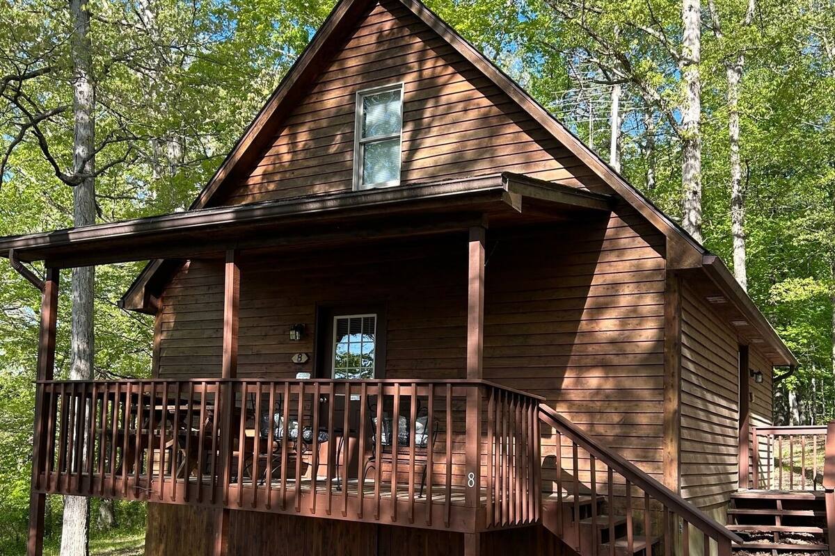 A wooden cabin with a porch, a staircase, and a small deck.
