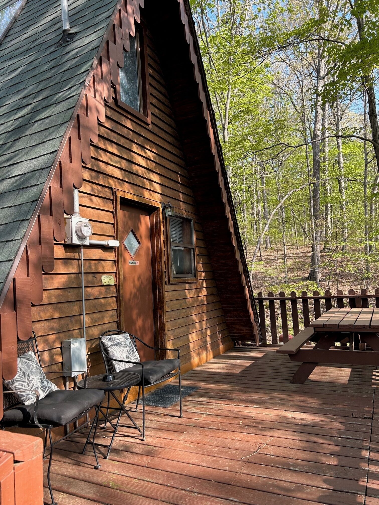 A rustic cabin with a wooden deck, outdoor seating, and a picnic table.