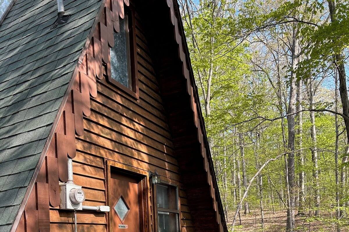 A rustic cabin with a wooden deck, outdoor seating, and a picnic table.