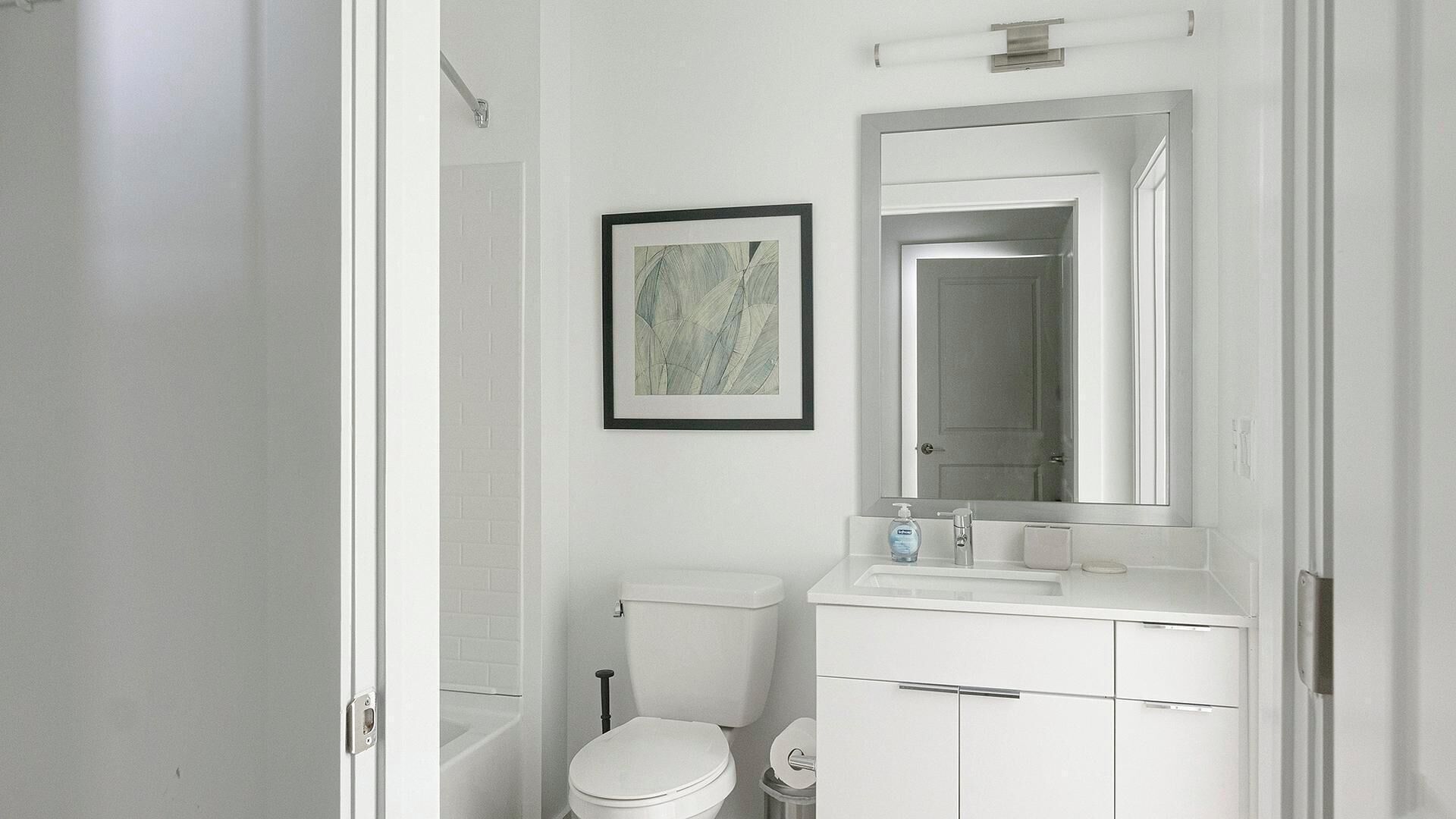 A bathroom with a toilet, sink, and mirror.