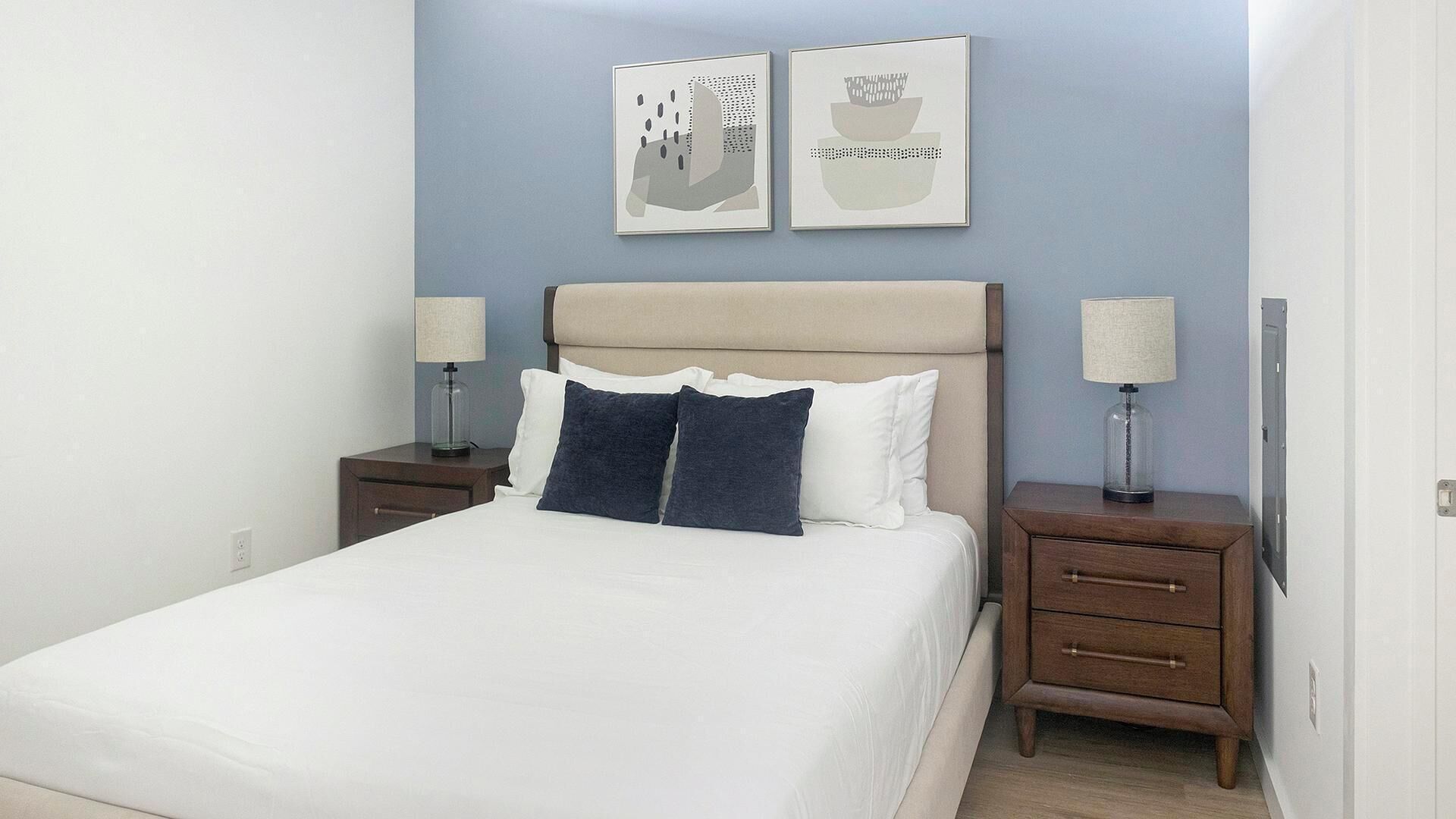 A neatly arranged bedroom with a bed, two bedside tables, and two wall-mounted lamps.