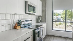 Una cocina moderna con armarios blancos, microondas integrado y un ventanal con vistas al exterior.