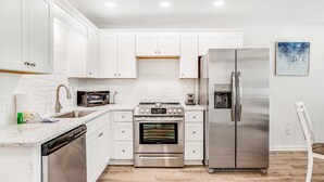 A modern kitchen with white cabinets, stainless steel appliances, and a dishwasher.