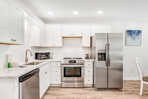 A modern kitchen with white cabinets, stainless steel appliances, and a dishwasher.