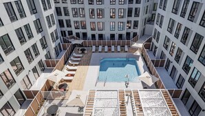 Un bâtiment moderne doté d’une piscine centrale, de nombreux balcons et d’espaces de détente en plein air.