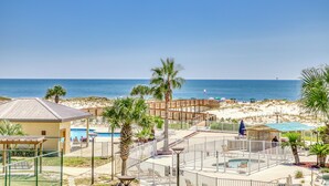 A beachside resort with a pool, palm trees, and a view of the ocean. - Waterfront condo with shared pool & hot tub - near dining & the beach (Fort Morgan)