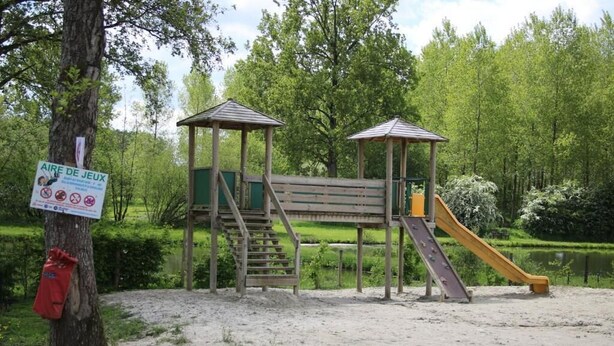 A playground with a wooden structure, a slide, and a staircase.