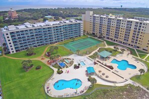 Un hôtel comprenant plusieurs étages, des piscines extérieures, des courts de tennis et des espaces paysagers.