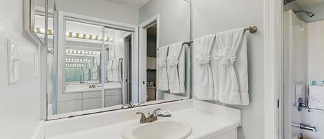 Un baño con un espejo grande, tocador, lavabo y perchero para toallas.