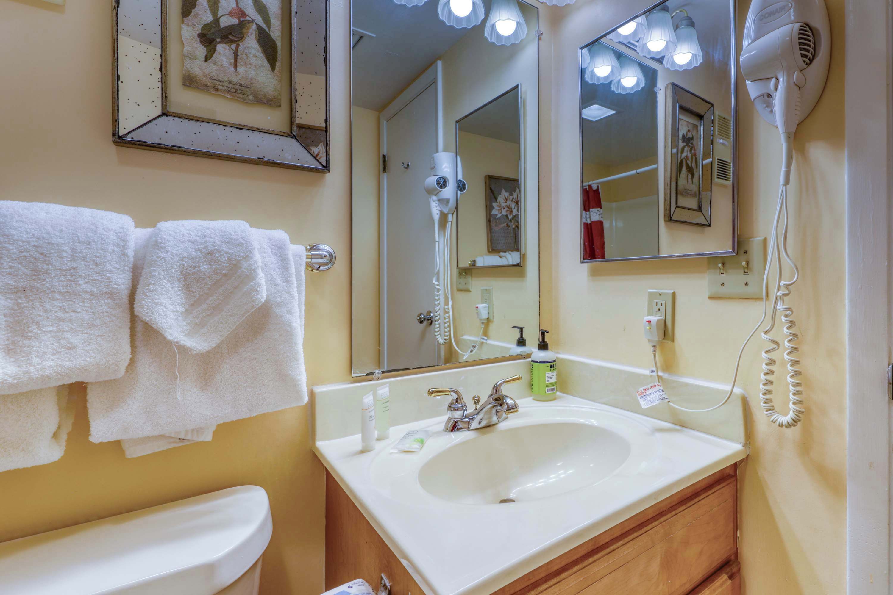 A bathroom with a sink, mirror, towel rack, and hair dryer.