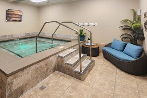 A spa area with a hot tub, a set of stairs, a wicker sofa with blue cushions, and a potted plant. - Plantation Dunes condo with Gulf views, pool, hot tubs & gym - walk to beach (Fort Morgan)