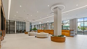 Un vestíbul ampli amb una zona de recepció, seients i grans finestres que ofereixen vistes cap a l'exterior.