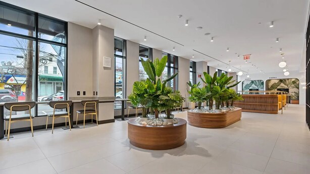 Un interior modern amb grans finestres, zones d'estar i plantes en testos.