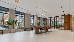 Un interior modern amb una taula de fusta al centre, plantes en testos i grans finestres.
