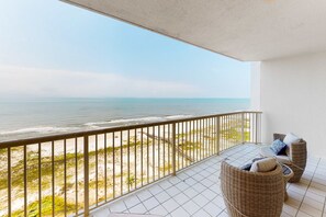 Ein Balkon mit Blick auf den Ozean, Korbmöbel und ein Fliesenboden.