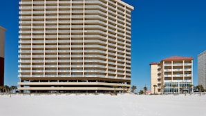 A multi-story hotel with a flat facade, numerous balconies, and a clear blue sky. - Waterfront home with a private deck, gas grill, WiFi, & central AC (Gulf Shores)