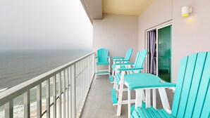 A balcony with a view of the ocean, teal chairs, and a glass door. - Waterfront home with a private deck, gas grill, WiFi, & central AC (Gulf Shores)